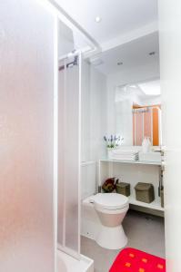 a white bathroom with a toilet and a red rug at Lisbon Core Bairro Alto Chiado in Lisbon