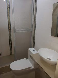 y baño con aseo blanco y lavamanos. en Hostal Aventura Total Perú_lunahuana, en Lunahuaná