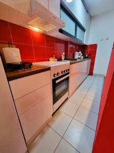 uma cozinha com paredes vermelhas e um fogão forno superior em A&P Apartments em Skopje
