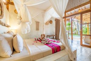 a bedroom with a canopy bed with flowers on it at Villa Burung Gili Air Authentic 3-Bedroom Bamboo Villa with Private Pool in Gili Air