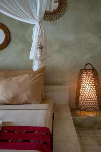 a bedroom with a bed with a white curtain and a lamp at Villa Burung Gili Air Authentic 3-Bedroom Bamboo Villa with Private Pool in Gili Air