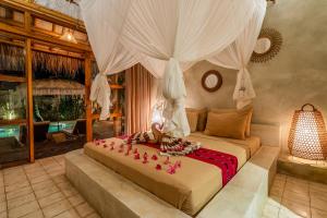 a bedroom with a bed with pink flowers on it at Villa Burung Gili Air Authentic 3-Bedroom Bamboo Villa with Private Pool in Gili Air
