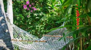 a hammock in front of a garden with flowers at Villa Burung Gili Air Authentic 3-Bedroom Bamboo Villa with Private Pool in Gili Air
