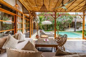 an outdoor patio with a table and a pool at Villa Burung Gili Air Authentic 3-Bedroom Bamboo Villa with Private Pool in Gili Air