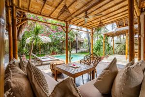 an outdoor living room with a table and chairs and a pool at Villa Burung Gili Air Authentic 3-Bedroom Bamboo Villa with Private Pool in Gili Air