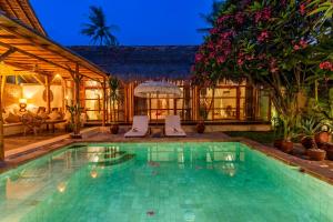 a swimming pool with two chairs in a house at Villa Burung Gili Air Authentic 3-Bedroom Bamboo Villa with Private Pool in Gili Air