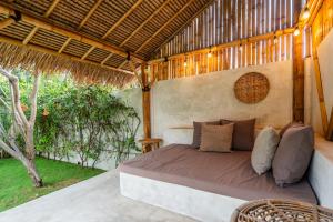a bed in a room with a thatched roof at Villa Burung Gili Air Authentic 3-Bedroom Bamboo Villa with Private Pool in Gili Air