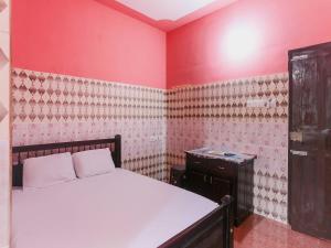 a bedroom with a bed and a red wall at OYO Hotel Sree Bhadra Tourist Home in Kollam