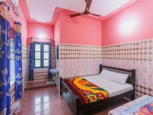 een slaapkamer met een bed in een kamer met roze muren bij OYO Hotel Sree Bhadra Tourist Home in Kollam