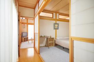 a bedroom with a bed and a desk with a television at Guesthouse Ichigo Ichie Nikko in Nikko