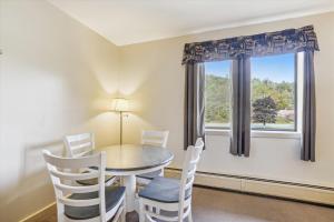 een eetkamer met een tafel en stoelen en een raam bij Cedarbrook Deluxe one bedroom suite with outdoor heated pool 21517 in Killington