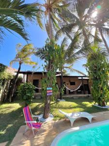 um resort com uma piscina e duas cadeiras e palmeiras em Butterfly House em Flecheiras