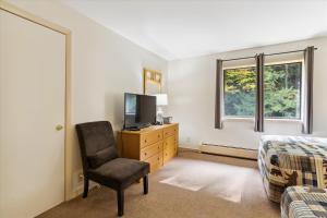 1 dormitorio con 1 cama, 1 silla y TV en Cedarbrook Two Double bed Standard Hotel room 217 en Killington