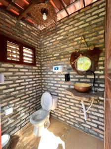 a brick bathroom with a toilet and a sink at Butterfly House in Flecheiras