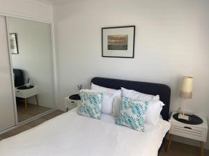 Un dormitorio con una cama blanca con almohadas azules y blancas en Conjola Inn-let - Self Contained Unit - Lake Conjola, en Manyana