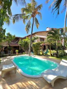a swimming pool with two chairs and a palm tree at Butterfly House in Flecheiras