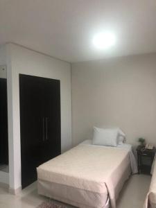 1 dormitorio con cama blanca y puerta negra en Ap em Alphaville maravilhoso, en Barueri