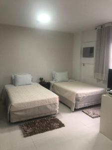 2 camas en una habitación blanca con 2 alfombras en Ap em Alphaville maravilhoso, en Barueri
