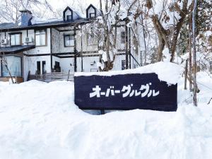 a sign in the snow in front of a house at Garden Pension Obergurgl in Hakuba