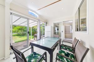 a dining room with a glass table and chairs at Archie s Abode By Coast Holidays in Patonga Beach