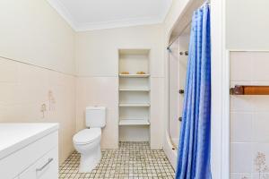 a white bathroom with a toilet and a shower at Archie s Abode By Coast Holidays in Patonga Beach