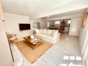a living room with a white couch and a table at Pearl House By Coast Holidays in Pearl Beach