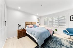 ein weißes Schlafzimmer mit einem Bett und einem blauen Stuhl in der Unterkunft Pearl House By Coast Holidays in Pearl Beach