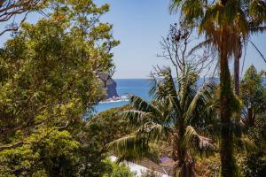 a view of the ocean through the trees at Aqua Vistas - Recharge on the Coast in Style in Macmasters Beach