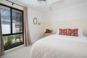 a bedroom with a white bed and a large window at Aqua Vistas - Recharge on the Coast in Style in Macmasters Beach