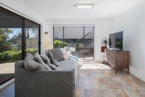 a living room with a gray couch and a television at Aqua Vistas - Recharge on the Coast in Style in Macmasters Beach