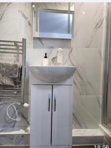 a white bathroom with a sink and a shower at Cozy Guest House in Kent