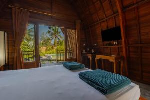 a bedroom with a bed with two green pillows on it at Kubu Selat Villa and Glamping in Gianyar