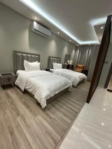 um quarto com 2 camas com edredões brancos em وسن الشرق em Dammam