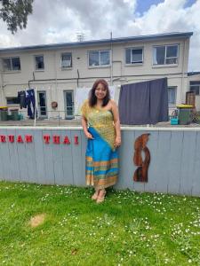 a woman in a dress standing next to a fence at Ruan Thai Bed and Coffee in Hamilton