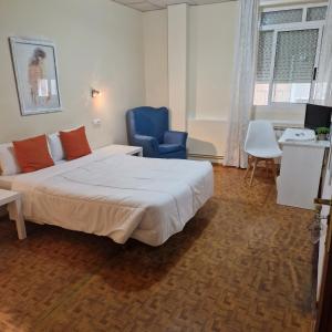 ein Schlafzimmer mit einem Bett und einem blauen Stuhl in der Unterkunft Hostal Real in Vigo