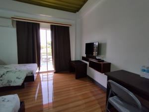 a hotel room with a bed and a tv and a room at RedDoorz @ LQJ Hotel Old Buswang Kalibo in Kalibo