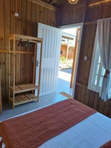1 dormitorio con 1 cama y puerta abierta en Cabanas MORIÁ en Garopaba