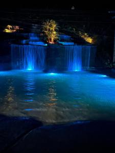 a pool of water with a waterfall at night at Hotel Fazenda Bavaria in São Lourenço