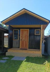 uma pequena casa com uma porta de madeira no quintal em Cabaña Los Pajaritos dos de Frutillar em Frutillar