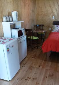 um quarto com um frigorífico, uma mesa e uma cama em Cabaña Los Pajaritos dos de Frutillar em Frutillar