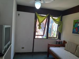 a room with a bed and a window and a television at Chalés Recanto da Praia in Caraguatatuba