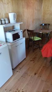 a kitchen with a microwave and a table with chairs at Cabaña Los Pajaritos dos de Frutillar in Frutillar
