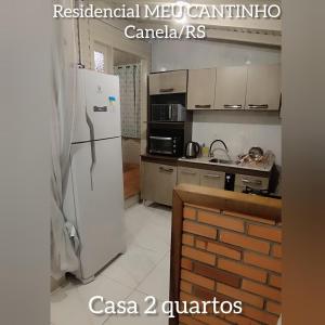 cocina con nevera blanca y fogones en RESIDENCIAL MEU CANTINHO en Canela