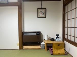a living room with a table and a television at AKANE Hostel あかね天然温泉旅館 in Mitsumata