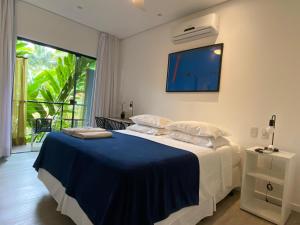 a bedroom with a bed with a tv on the wall at Pousada Armação de Camburi in Camburi