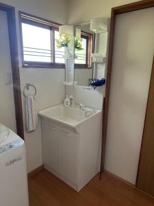 ein weißes Badezimmer mit einem Waschbecken und einem Spiegel in der Unterkunft Minpaku Tanaka - Vacation STAY 15255 in Kyōtango