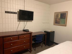 een slaapkamer met een bureau en een tv aan de muur bij Franklin Motel in Assiniboia