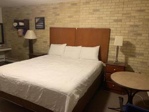 een slaapkamer met een groot bed met witte lakens en een tafel bij Franklin Motel in Assiniboia
