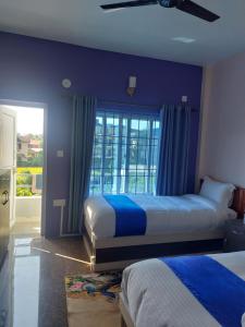 a bedroom with two beds with blue walls and a window at Hotel Namo Buddha in Sauraha