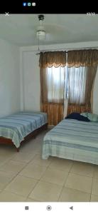 a bedroom with two beds and a window with curtains at Hospedaje Portobelo in Portobelo